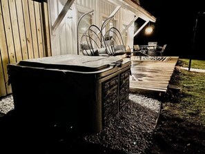 Ein Whirlpool vor einem Gebäude mit einer Holzterrasse und Stühlen.