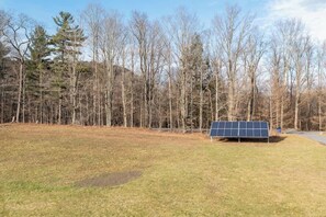 A solar panel installation in a grassy area with trees in the background.