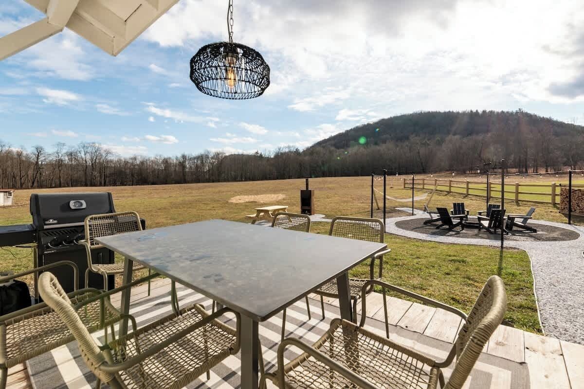 Un patio al aire libre con una mesa, sillas, una parrilla y un colgador de luces.