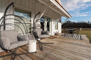 Eine Holzterrasse mit zwei Schaukelstühlen und einem Esstisch.