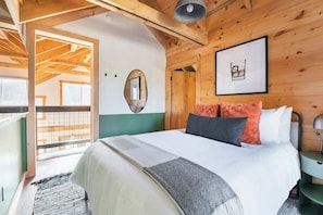 A bedroom with a bed, a bedside table, a mirror, and a framed picture on the wall. - The Bar(n)- Cozy chalet with hot tub and campfire (Brooktondale)