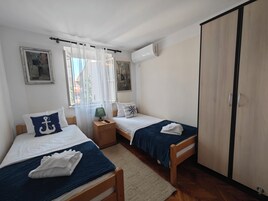Una habitación con dos camas, una mesita de noche, una lámpara y un armario.
