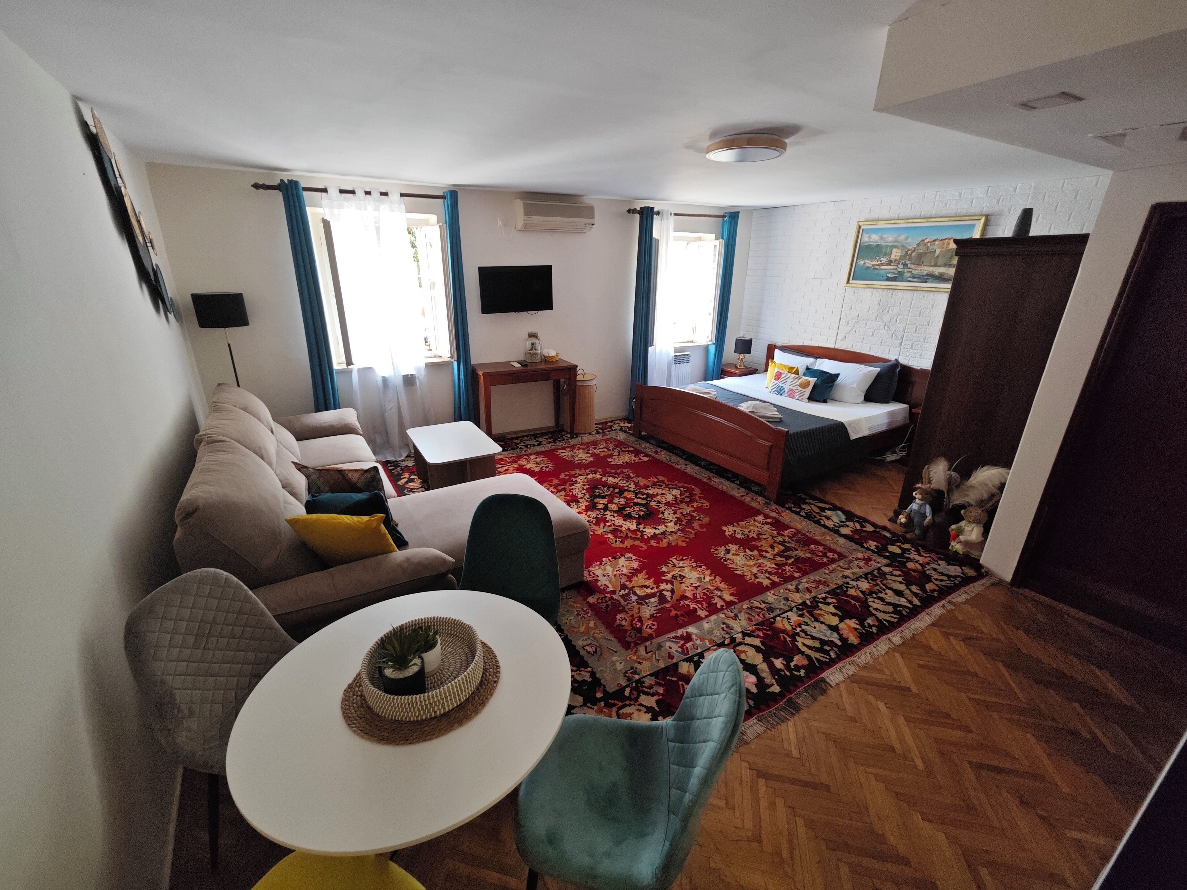 Ett kompakt hotellrum med en säng, en soffa, ett litet bord och en stol.