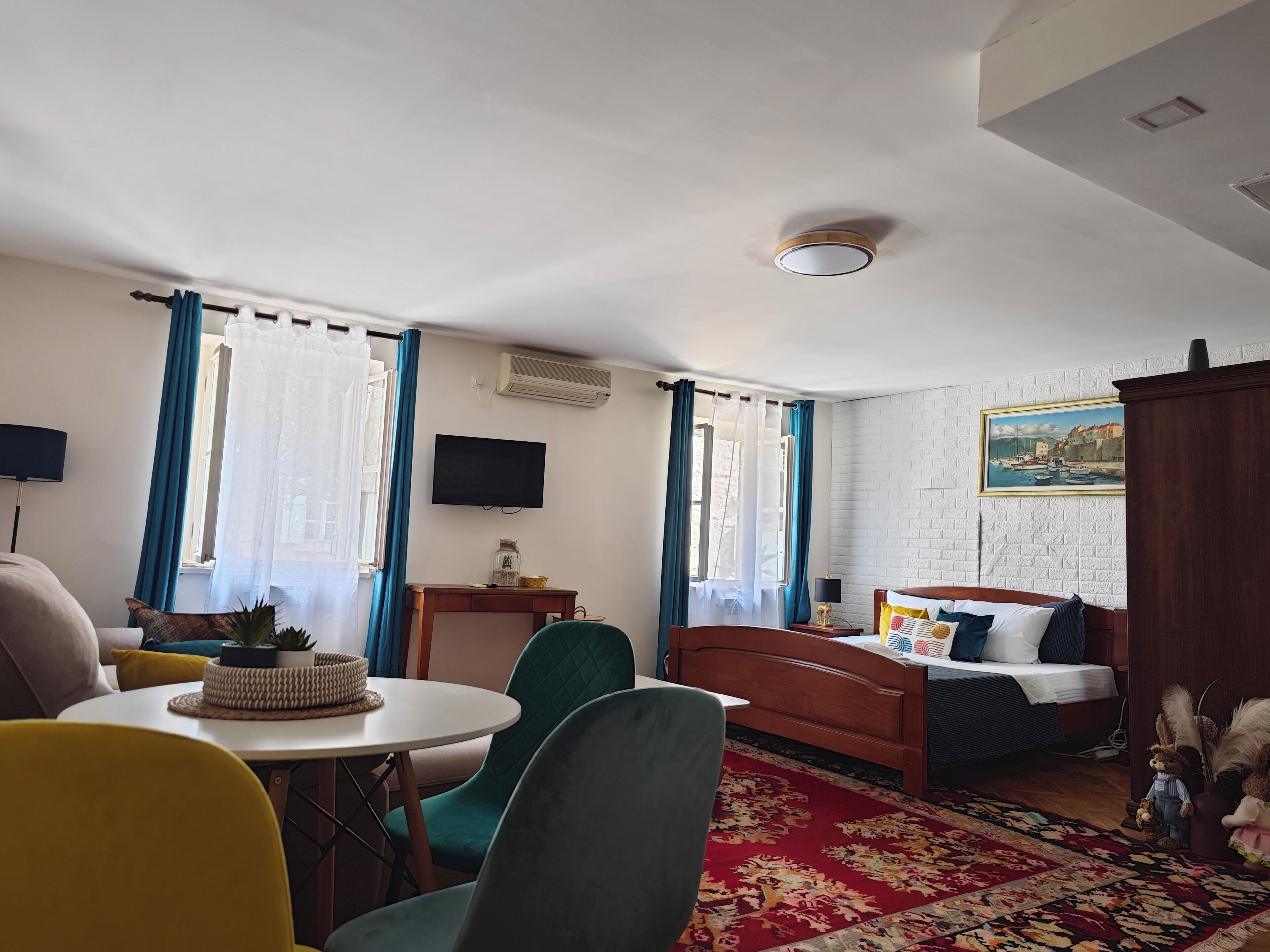 Habitación de hotel con cama, televisión, escritorio y zona de comedor con sillas y mesa.