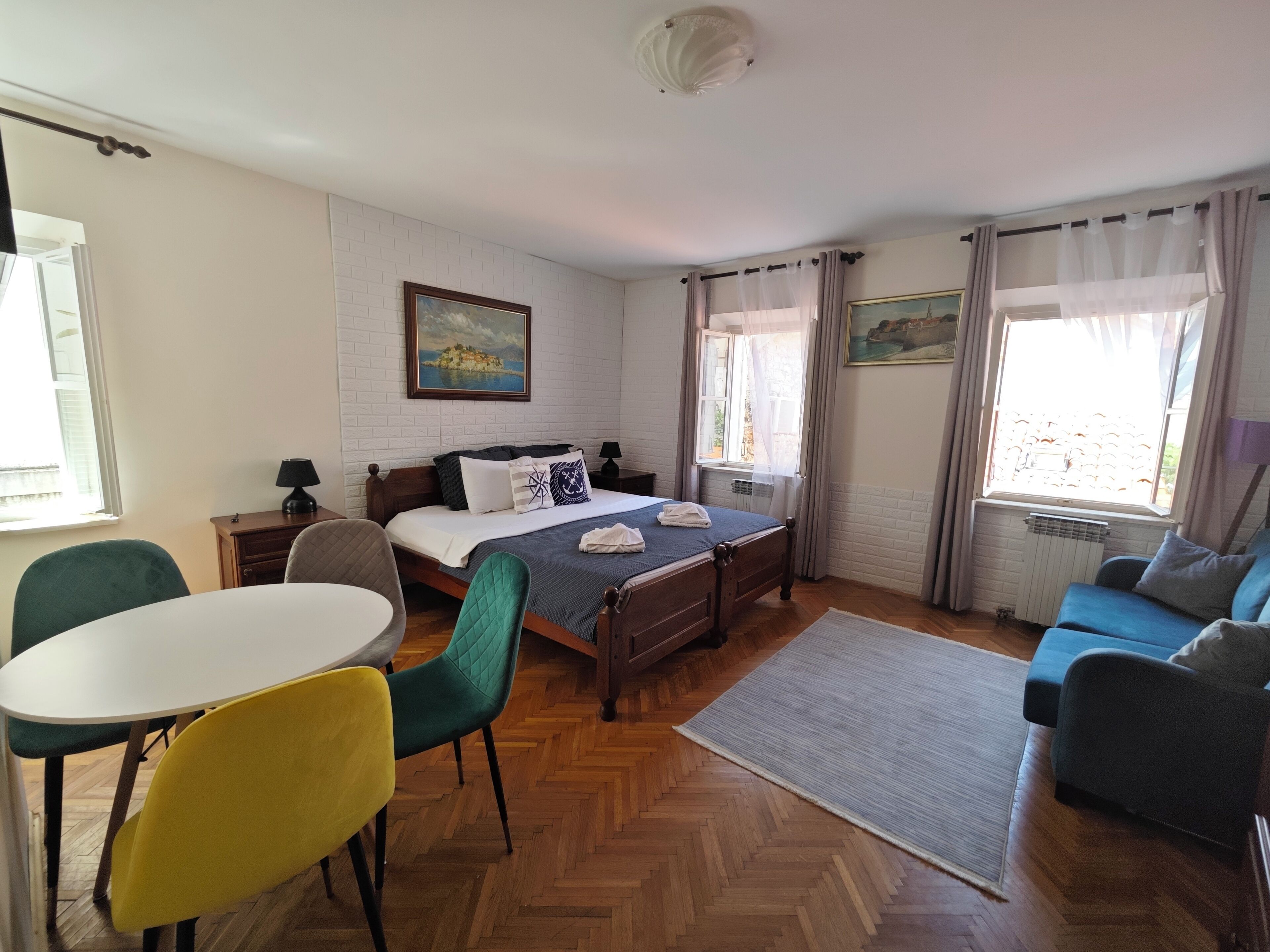 Een slaapkamer met een bed, een bureau, een stoel, een bank en een raam met gordijnen.