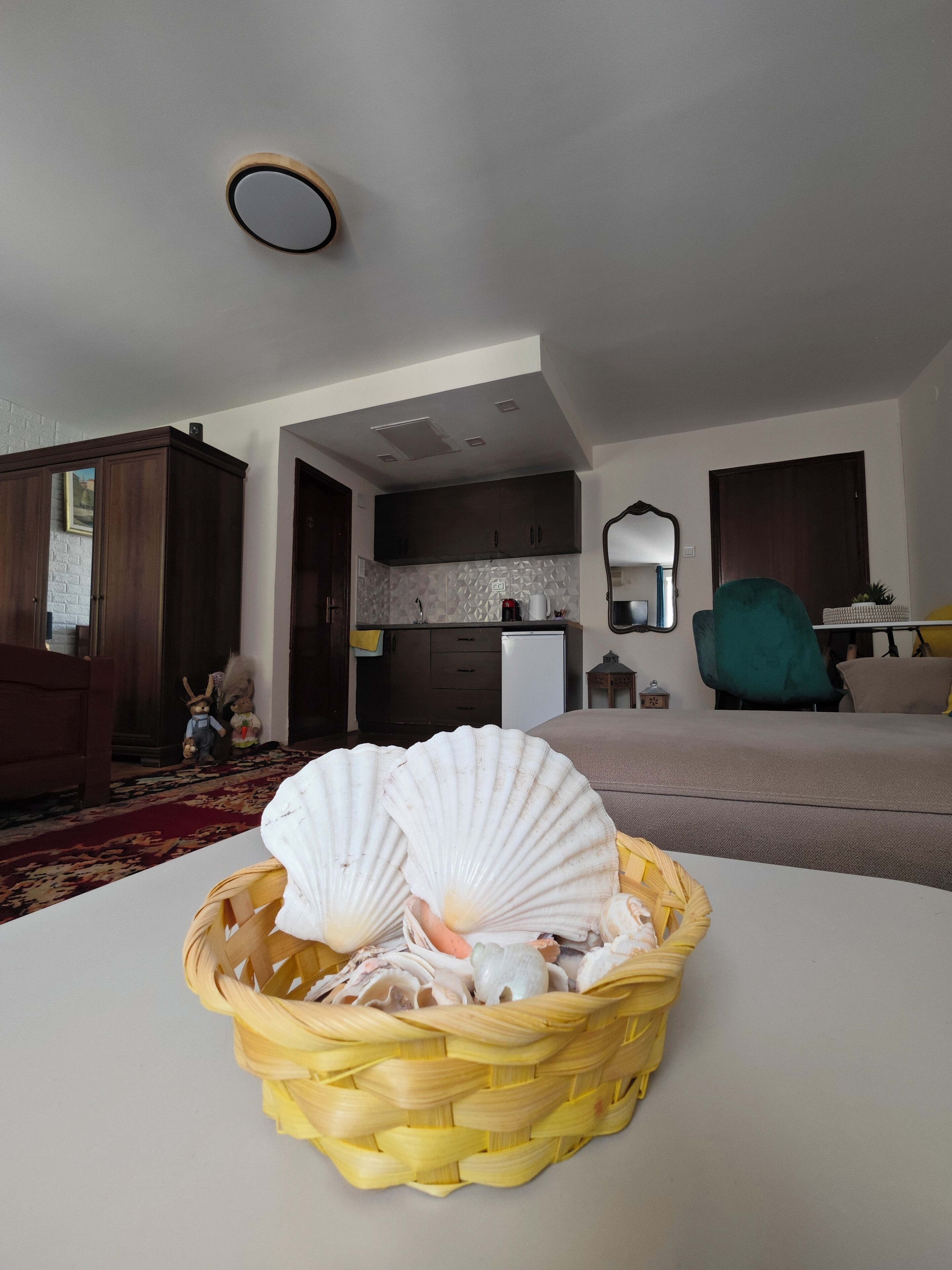 Een woonkamer met een eethoek, een keuken en een grote spiegel.