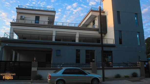 Um edifício moderno de dois andares com um carro estacionado na frente.