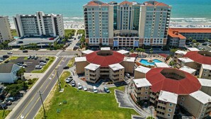 A hotel with multiple buildings, a parking lot, and a view of the beach. - Beautiful Coastal Retreat in North Myrtle Beach - Steps from the Ocean (North Myrtle Beach)