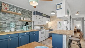 A modern kitchen with blue cabinets, a wooden island, and a stone backsplash. - Beautiful Coastal Retreat in North Myrtle Beach - Steps from the Ocean (North Myrtle Beach)