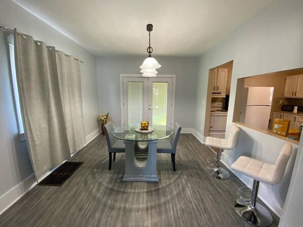 A compact kitchen with a dining area, featuring a round glass table, two bar stools, and a pendant light. - Niles Spacious 2-Story Family & Work Haven (Niles)