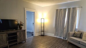 A living room with a flat-screen TV, a floor lamp, a sofa, and a door leading to another room. - Niles Spacious 2-Story Family & Work Haven (Niles)