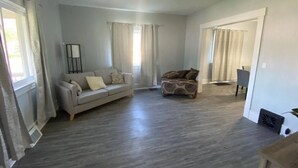 A spacious living room with a grey sofa, a patterned armchair, and a small table. - Niles Spacious 2-Story Family & Work Haven (Niles)