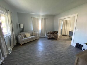 A spacious living room with a grey sofa, a patterned armchair, and a small table. - Niles Spacious 2-Story Family & Work Haven (Niles)