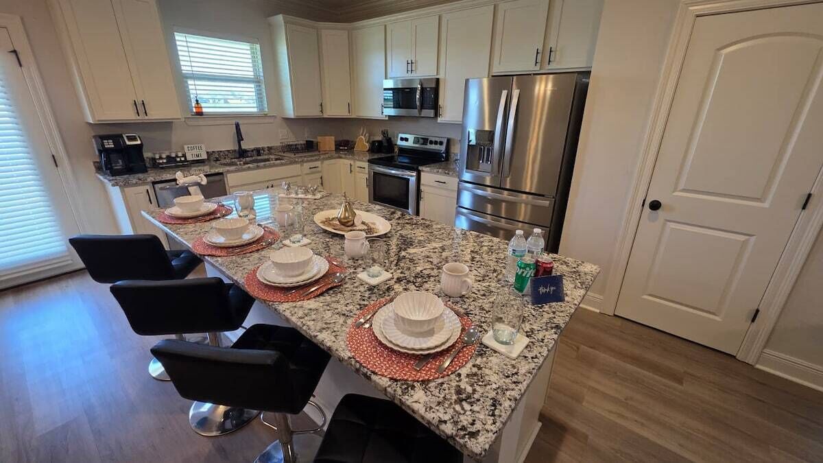 A modern kitchen with granite countertops, stainless steel appliances, and a dining area set for four.