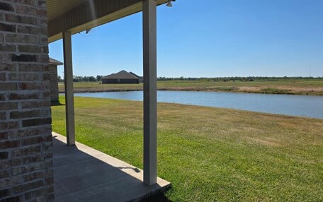 A covered outdoor area with a brick wall, a concrete floor, and a view of a body of water and distant buildings.