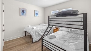 A room with a bunk bed, a single bed, and two framed pictures on the wall.