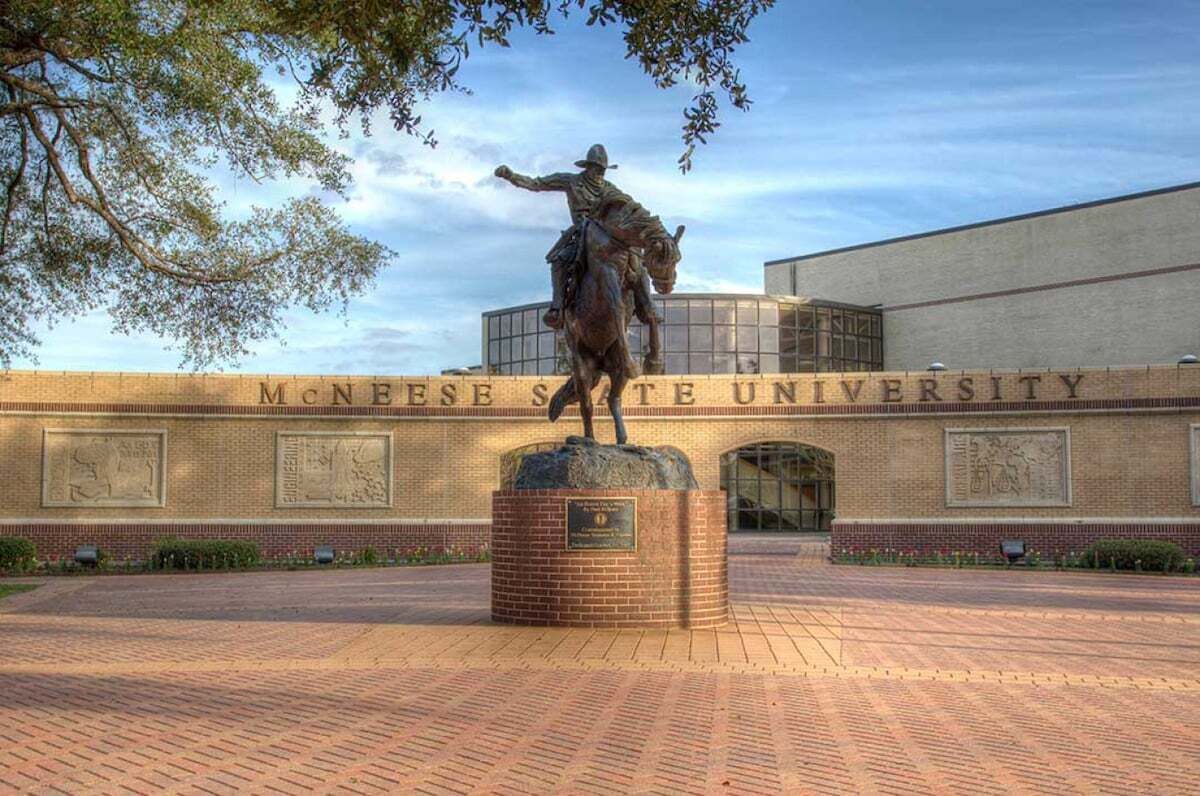 A statue of a mounted figure in front of a building with 'McNeese State University' written on it.