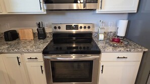 A kitchen with a stainless steel stove, oven, and microwave. There are cabinets, a toaster, and a knife block on the countertop.