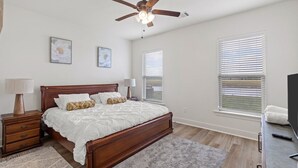 A bedroom with a wooden bed, a ceiling fan, a TV, and a window with blinds.
