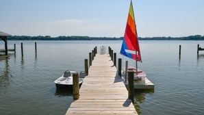 A wooden pier extending into calm water with a sailboat docked at the end.