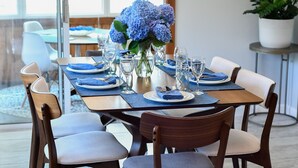 A dining table set for six with blue napkins, white plates, and clear glassware.