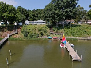A lake with a wooden dock, a sailboat, and a small rowboat. - Waterfront Game-Themed Getaway · Dock & Kayaks (Montross)