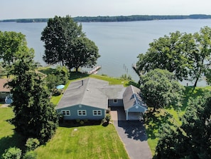 A residential property with a two-story house, a covered patio, and a dock extending into a lake. - Waterfront Reset: Views, Games, Boats & Total Calm (Montross)