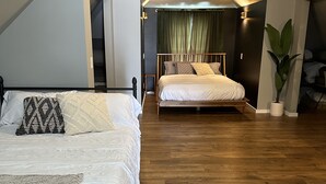 Ein Schlafzimmer mit zwei Betten, Holzboden, Deckenventilator und einer Topfpflanze.