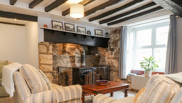 Una sala de estar acogedora con sillones a rayas, una mesa de centro de madera, una chimenea de piedra y cuadros enmarcados en la pared.