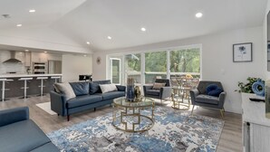 Ein modernes Wohnzimmer mit einem blauen Sofa, einem runden Couchtisch und einem Essbereich mit einem Glastisch.