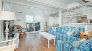 A spacious living room with a large sofa, a coffee table, and a dining area. - 2910 - Dolphin's Den, Duck Condo | Pools, Tennis & Views (Duck)