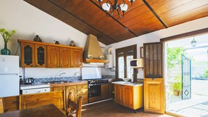 A kitchen with wooden cabinets, a stove, and a dining area with a table and chairs. - Cubo's Casa Rural Jose & Caminito del Rey / Piscina privada / Caminito del Rey (Ardales)