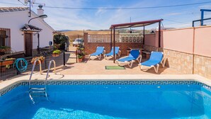 A swimming pool with lounge chairs, a covered patio, and a view of the countryside. - Cubo's Casa Rural Jose & Caminito del Rey / Piscina privada / Caminito del Rey (Ardales)