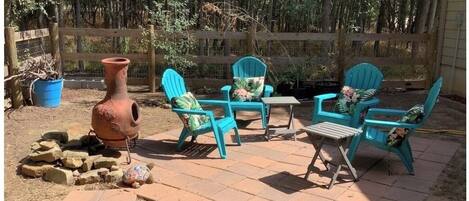 Une terrasse extérieure avec des chaises turquoise, une table et un pot en terre cuite.