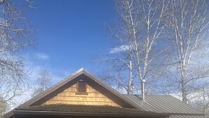 Eine Holzhütte mit Veranda, zwei Adirondack-Stühlen und einem Kiesweg zum Eingang.