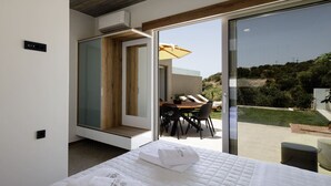 A modern bedroom with a bed, a dining area with a table and chairs, and a sliding glass door leading to a patio.