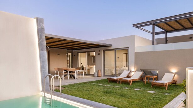 A modern outdoor pool area with a grassy lawn, lounge chairs, and a dining area.
