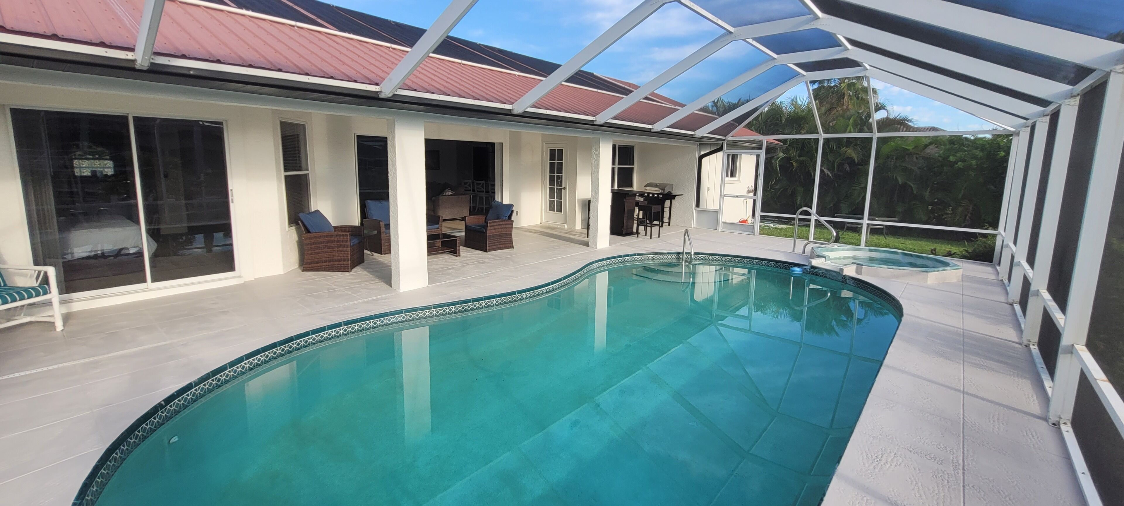 A covered swimming pool with lounge chairs and a patio area.