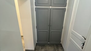 En smal hall med grå dubbeldörrar och ett klinkergolv.