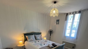 Ett sovrum med en säng, sänglampor, en golvlampa, ett fönster och ett element.