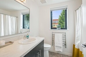 Un baño moderno con un lavabo blanco, un espejo, una ventana y un inodoro.