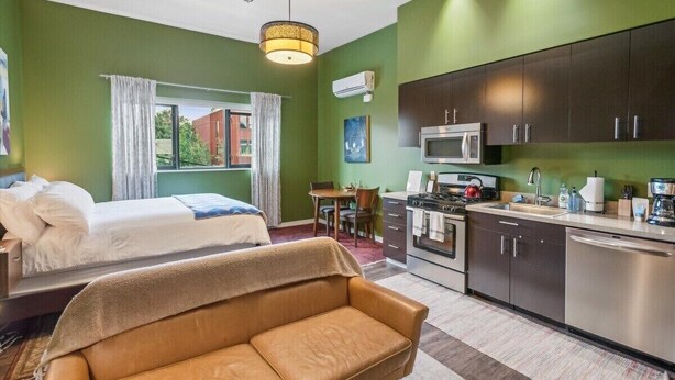 A room with a bed, a sofa, a dining table, and a kitchenette. - Quiet End-Unit Studio w/ Full Kitchen + Natural Light (Portland)
