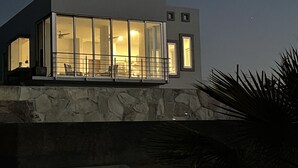 Une maison moderne avec une façade en pierre, de grandes fenêtres et un balcon.