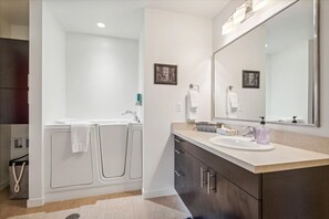 A modern bathroom with a bathtub, a sink, and a large mirror. - Colorful 2BR/2BA w/ King Bed, Local Art + Secure Parking (Portland)