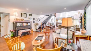 A spacious living room with a piano, wooden chairs, a sofa, and a staircase leading to an upper floor. - Spacious & Secluded Shook Home w/ Private Hot Tub! (Shook)