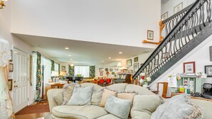 A spacious living room with a large sectional sofa, a staircase with a wrought iron railing, and a dining area in the background. - Spacious & Secluded Shook Home w/ Private Hot Tub! (Shook)