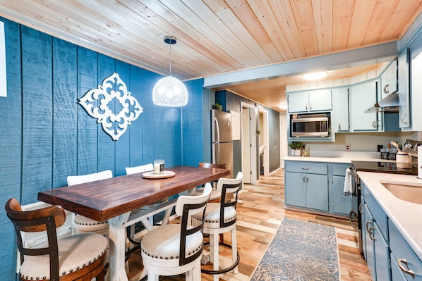 Una cocina moderna con armarios azules, una mesa de comedor de madera y sillas blancas.