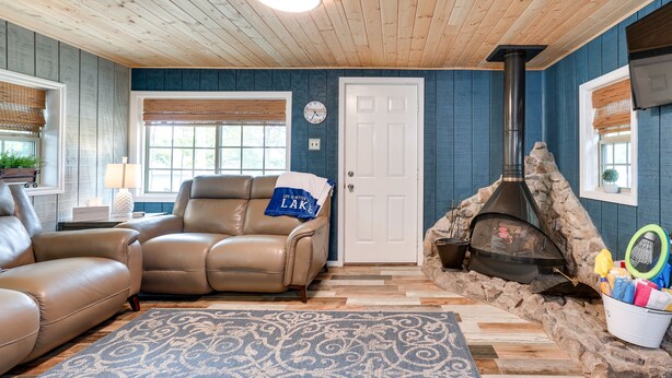 A cozy living room with a stone fireplace, leather sofas, and a patterned rug.