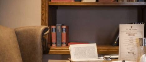 A room with a wooden bookshelf, a leather chair, and a menu on the table.