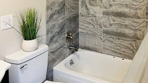 Een badkamer met toilet, wastafel en bad.